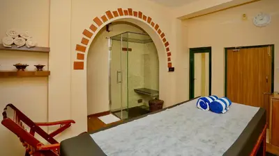 a room with a table and a glass shower at Hotel Vivek in Coonoor