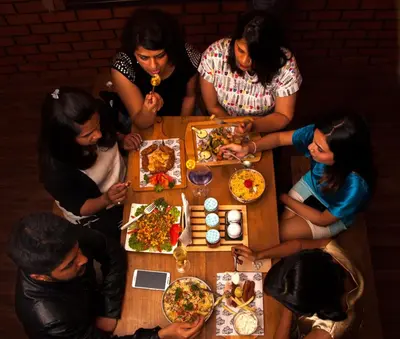 a group of people sitting around a table eating food at Hotel Vivek in Coonoor