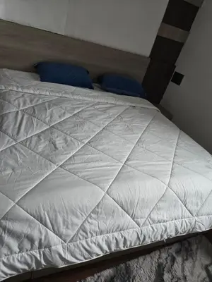 a white bed with blue pillows in a bedroom at Shan Home Stay in Mysore