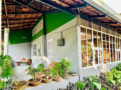 a green and white house with potted plants at Massbungalow in Tindummal