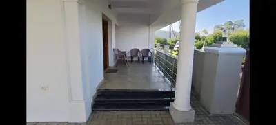 a porch of a house with stairs and chairs at Sathya Holidays Evermist Stay in Ooty