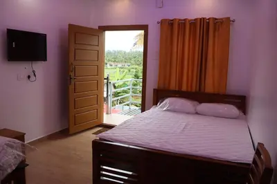 a bedroom with a bed and a door with a balcony at Carmel Cottage in Marayoor