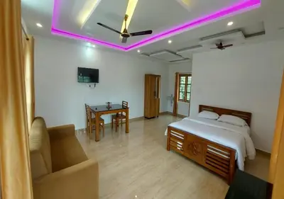 a bedroom with a bed and a couch and a table at Carmel Cottage in Marayoor