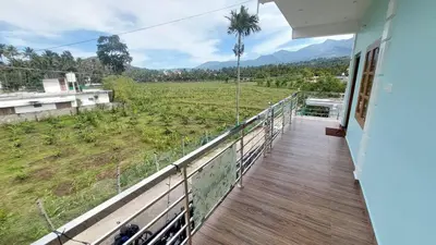 a balcony of a house with a view of a field at Carmel Cottage in Marayoor