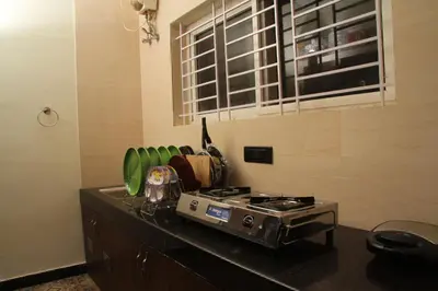 a kitchen counter with a stove and green chairs at Luxurious Private Vantage Villa - Kotagiri in Kotagiri