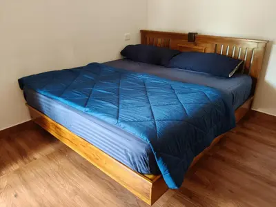 a bed with blue sheets and a wooden headboard at River View Resort, Nilambur in Nilambūr