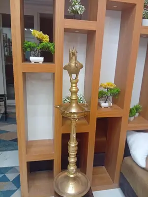 a bookcase with a brass trophy in a room at Gurunandanam-Fully furnished Deluxe Apartment East Nada Guruvayur in Guruvāyūr