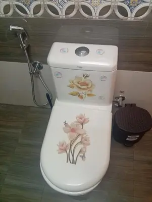 a toilet with flowers painted on it in a bathroom at Gurunandanam-Fully furnished Deluxe Apartment East Nada Guruvayur in Guruvāyūr
