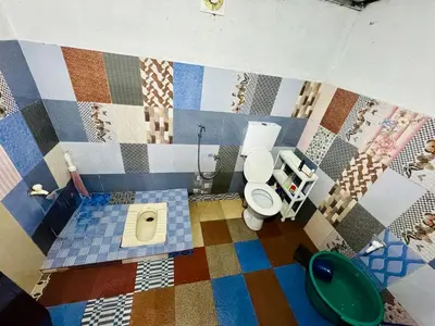 a bathroom with a toilet and a mosaic wall at Parathanathu Homestay in Viripara
