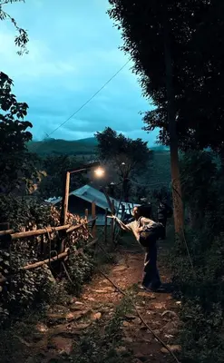 a woman standing on a dirt road with a pole at Misty Colina in Kottakamboor