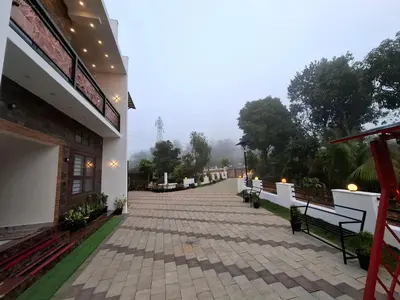 a walkway in front of a building with benches at RiverBank Gardens, Mananthavady, Wayanad in Mananthavady