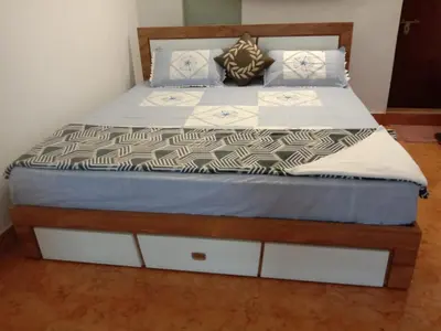 a bed with white and brown sheets and pillows on it at NEST nature homestay in Kalpetta