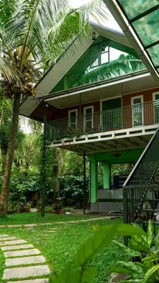 a house with a balcony and a palm tree at NEST nature homestay in Kalpetta