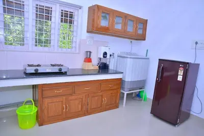 a kitchen with a counter and a refrigerator in it at Lead Homestay Chalakudy in Kizhake Chālakudi