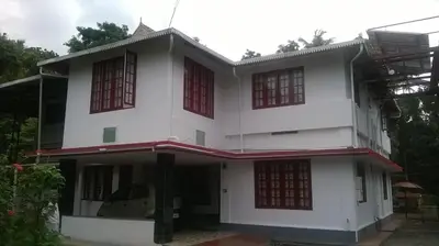 a white house with red windows at Lead Homestay Chalakudy in Kizhake Chālakudi