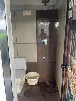 a bathroom with a toilet and a person in a window at Tulips villa in Mānantoddy
