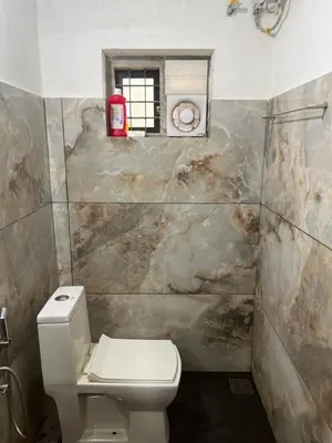 a bathroom with a white toilet and a window at Tulips villa in Mānantoddy