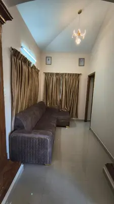 a living room with a couch in front of a window at Hideout luxe in Ooty