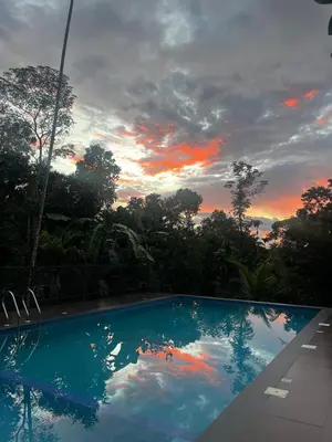 a swimming pool with a sunset in the background at Avocado Orchards - Villa in Kenichira