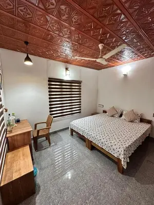 a bedroom with a bed and a table and a desk at Avocado Orchards - Villa in Kenichira
