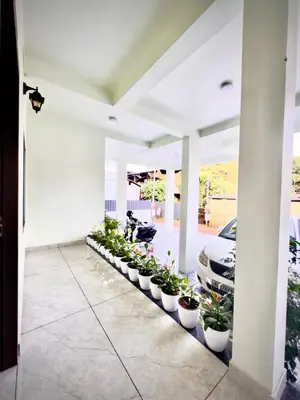 a row of potted plants in a hallway with a car at Tokyoz Inn Calicut in Kunnamangalam