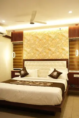 a bedroom with a large white bed and a wall at Elite Group Mysore in Mysore