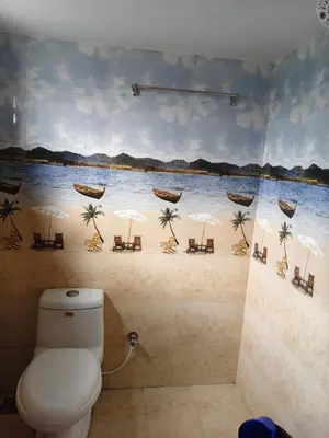 a bathroom with a toilet and a mural of a beach at Hridayam Hill view nest in Marayoor