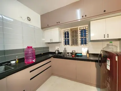 a kitchen with white cabinets and black counter tops at Namasv 2BHK AC House in Narasimharaja Puram