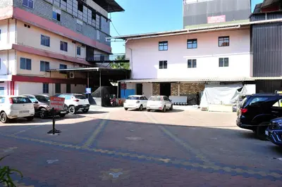 a parking lot with cars parked in front of a building at Alfa Tourist Home, Batheri in Sultan Bathery