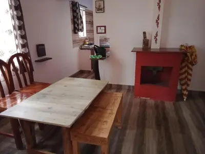 a living room with a wooden table and a red fireplace at Avichala in Mysore