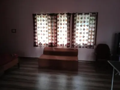 a room with a couch in front of two windows at Avichala in Mysore