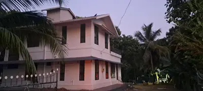 a white building with black windows and palm trees at Sthala Organic Farm Stay in Nallepilli