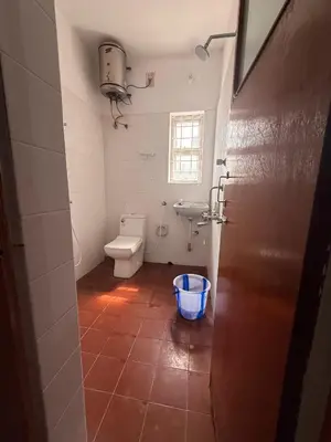 a bathroom with a toilet and a bucket on the floor at Western Castle Stay n lawn in Coimbatore