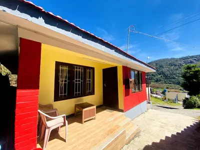 a colorful house with a chair on a wooden deck at Skyline Haven cottage ll in Ooty