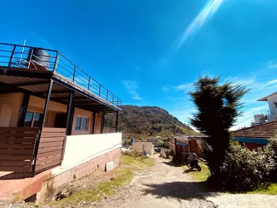 a tree in front of a building with a mountain in the background at Skyline Haven cottage ll in Ooty
