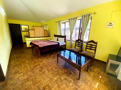 a living room with a bed and a table at Skyline Haven cottage ll in Ooty
