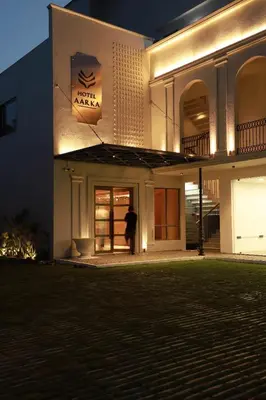 a man standing outside of a building at night at Hotel Aarka in Mettuppālaiyam