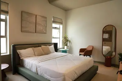 a bedroom with a bed and a mirror and a chair at Hotel Aarka in Mettuppālaiyam