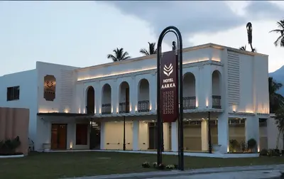 a white building with a sign in front of it at Hotel Aarka in Mettuppālaiyam