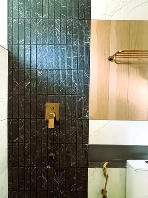 a bathroom with a black tiled wall next to a toilet at Hotel Aarka in Mettuppālaiyam
