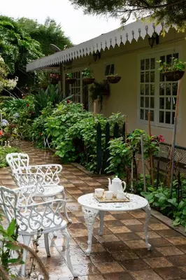 a patio with two chairs and a table with a tea kettle on it at SaffronStays Oakridge Cottage in Coonoor