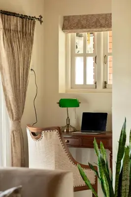 a living room with a chair and a desk with a laptop at SaffronStays Oakridge Cottage in Coonoor