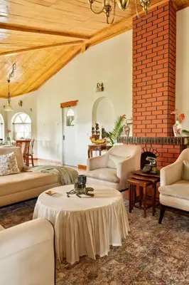 a living room filled with furniture and a brick wall at SaffronStays Oakridge Cottage in Coonoor