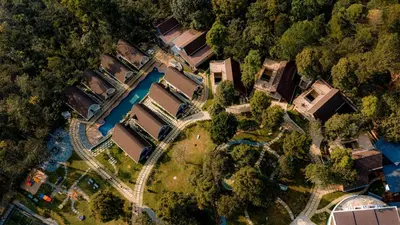 an overhead view of a yard with houses and a river at Golf Valley Luxury Resort Wayanad in Vythiri