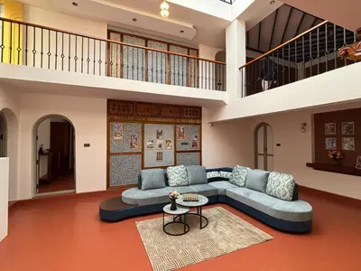 a large living room with a blue couch and a table at Burnside Cottage in Kotagiri