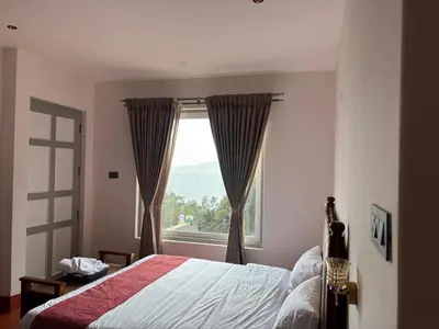 a bedroom with a bed and a large window at Burnside Cottage in Kotagiri