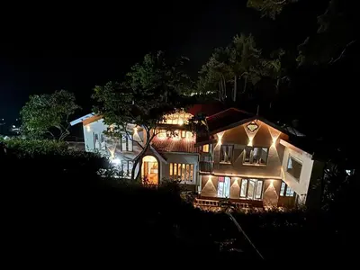 a large house with lights on at night at Burnside Cottage in Kotagiri