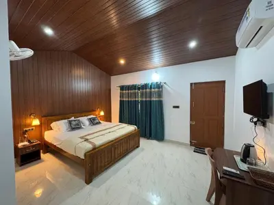a bedroom with a bed and a television in it at Manuvan Estate Stay in Kushālnagar