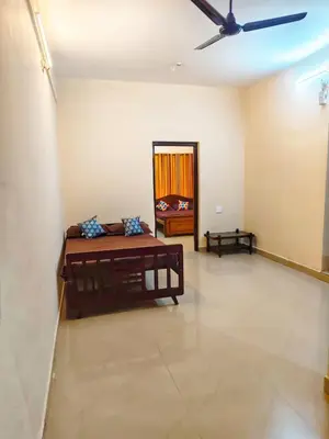 a living room with a bed and a ceiling fan at Sri Parthasarathy Inn in Guruvāyūr