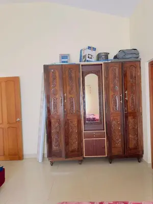 a set of wooden cabinets with a mirror in a room at Whitelily's Amrithasthanam in Madikeri